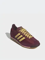 Zapatillas Adidas SL 72 OG W, color borgoña con rayas amarillas y detalles en fucsia. Inspiradas en el modelo original de 1972, con exterior de piel y revestimientos de gamuza.