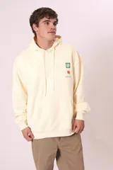Sudadera con capucha de color verde oscuro (o verde petróleo) con efecto lavado, corte holgado y bolsillo canguro. Presenta un pequeño bordado blanco en el pecho con un diseño floral y texto.