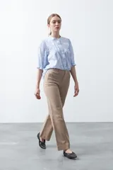 Pantalón negro de tiro alto, corte recto y silueta clásica. Presenta costuras verticales marcadas en la parte delantera de las piernas.