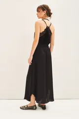 Falda midi negra con tajo lateral, breteles finos y escote en V con encaje.