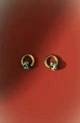 Aros tipo argolla de metal dorado con un dije colgante en forma de cuenta ovalada con estampado dálmata (blanco y negro).