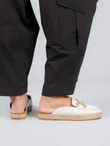 Sandalia mule color blanco con aplique metálico dorado y suela de yute.