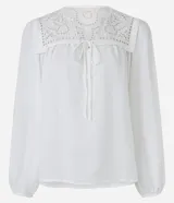Blusa blanca amplia de viscosa, con lazo delantero, mangas largas abullonadas y canesú con encaje richelieu.