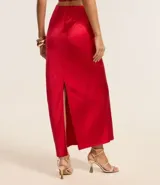 Vestido largo de satén color crema, con escote halter, espalda descubierta y abertura frontal. Presenta detalles de pedrería en el escote.