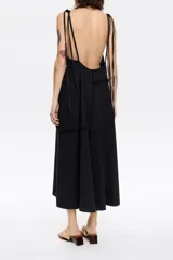 Vestido midi negro de corte recto y tirantes finos, con paneles y detalles desflecados.