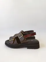 Sandalias de cuero color chocolate con plataforma track negra y hebillas metálicas plateadas.