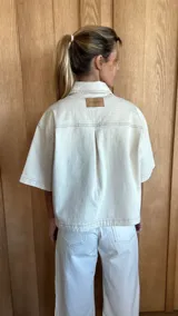 Sobrecamisa color gris oscuro de denim suave, con cuello clásico, cierre frontal con botones, mangas cortas y dos bolsillos de parche en el pecho.