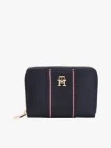Billetera Tommy Hilfiger azul marino con cierre de cremallera, detalle de tejido trenzado, múltiples ranuras interiores para tarjetas, compartimento interior con cremallera e insignia del monograma TH dorada en la parte delantera.