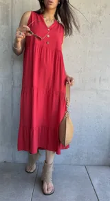 Vestido midi rojo sin mangas con botones decorativos en el escote y corte escalonado.