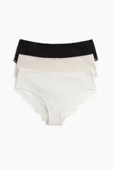 Pack de tres bombachas hipster de algodón suave, con cintura estándar, cobertura media y ribetes de encaje. Incluye una bombacha negra, una color crema y una blanca.