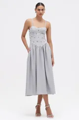 Vestido midi gris con rayas verticales plateadas, busto tipo corsé con tirantes finos y falda acampanada. Decorado con cristales y pedrería formando arreglos florales.