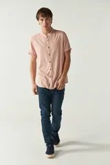 Camisa lisa color salmón con cuello mao y mangas cortas con dobladillo.