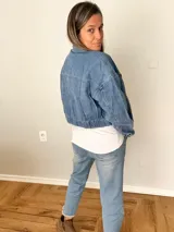 Campera de jean celeste con corte corto y fit relajado, botones metálicos frontales, bolsillos con solapa y espalda con elástico fruncido.