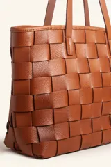 Cartera tipo tote bag de cuero vacuno trenzado a mano, con diseño de tejido ajedrez. Cuenta con doble asa de hombro y cierre superior.