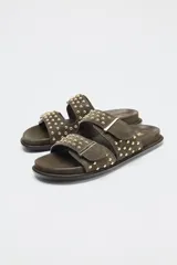 Sandalias planas color verde militar con doble tira con hebillas y tachas metálicas.