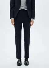 Pantalón de vestir azul marino, de corte recto, con bolsillos laterales y traseros. Se ajusta a la cintura con cinturón de cuero marrón.