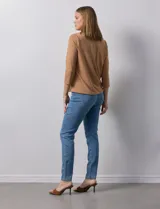 Blusa blanca de poliéster y elastano, con cuello a la base, escote en V y mangas tres cuartos. Presenta dos bolsillos frontales con cierre metálico dorado.