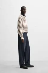 Sweater de punto color crudo con rayas horizontales marrones, de corte relaxed fit, cuello redondo y mangas largas con terminaciones en rib.