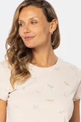 Remera color beige con estampado de aves en tonos celeste, lila y dorado.