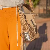 Cartera de cuero vacuno en tonos camel y peltre, con manija corta y correa larga ajustable, ideal para uso como cartera o morral.