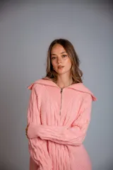 Buzo de punto color rosado, con cuello polo y cierre frontal parcial, de manga larga y diseño holgado.