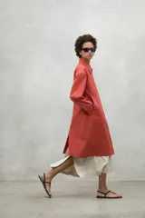 Chaqueta color beige, repelente al agua, con cuello clásico, cierre con botones, bolsillos laterales y corte holgado. Fabricada con poliéster reciclado y algodón orgánico.