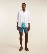 Bermuda de baño celeste y azul, de microfibra, con cintura elástica ajustable con cordón, bolsillos laterales y bolsillo trasero con cierre de cremallera.