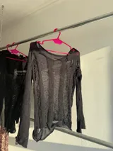 Buzo de malla negra con diseño holgado y manga larga.