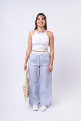 Pantalón de tela a rayas verticales celestes y blancas, con corte amplio, cintura elástica y cordón ajustable.