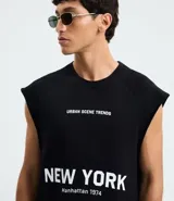 Musculosa negra de algodón con corte recto y hombros ligeramente ampliados (boxy fit). Presenta estampado frontal en blanco con el texto "URBAN SCENE TRENDS", "NEW YORK" y "Manhattan 1974".