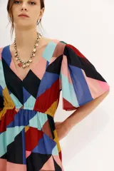 Vestido midi de gasa estampada con diseño geométrico multicolor, mangas cortas y elástico en la cintura. Tiene tajo frontal y forro en la falda.