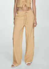 Pantalón color beige de tiro medio y corte ancho, con bolsillos laterales, bolsillos cargo y bolsillos de parche en la parte posterior.