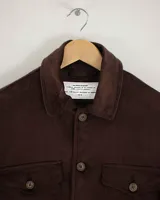 Camisa de pana color beige, de manga larga, con cuello camisero, cierre frontal de botones y dos bolsillos de parche con solapa en el pecho. Presenta un corte recto y holgado.