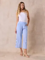 Pantalón blanco de algodón con pretina elastizada, bolsillos inclinados y ruedo lateral con tajo y botones.