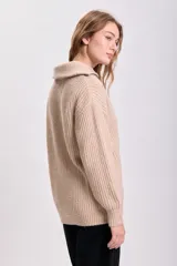 Sweater beige de punto grueso, con cuello polo y cierre metálico parcial.
