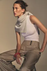Pantalón de tiro alto color beige, con bolsillos delanteros y falsos bolsillos traseros. Pierna ancha y cierre frontal con ganchos metálicos y botones.