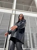 Blazer oversize de ecocuero color negro, con mangas largas con botón (tipo camisa) y bolsillos amplios delanteros.