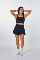 Conjunto deportivo negro compuesto por un top con logo "bk." y una falda corta con short interno.