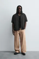 Pantalón de jean color beige, de corte ancho y tiro medio, con cinco bolsillos, efecto lavado y cierre frontal con cremallera y botón.