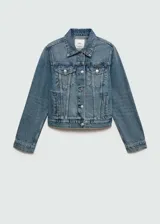 Chaqueta de jean azul de corte recto con cuello camisero, cierre frontal con botones metálicos, dos bolsillos con solapa en el pecho y mangas largas con puños abotonados.