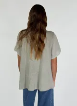 Camisa de lino y algodón color rosa claro, con cuello en V, mangas cortas y volados frontales.