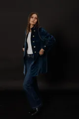 Chaqueta azul de terciopelo con corte levita, cuello mao y doble botonadura dorada.