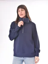 Buzo de punto color rosa con cuello alto con cierre de cremallera metálica y mangas largas abullonadas.