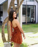 Vestido corto color fucsia con escote en V, breteles finos que se atan al cuello, corte a la altura de la cadera y falda acampanada con ruedo irregular.