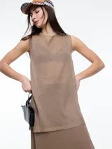 Musculosa color dorado, tejida en lurex, sin mangas, de calce holgado y largo por debajo de la cadera. Presenta aberturas laterales y tejido translúcido.