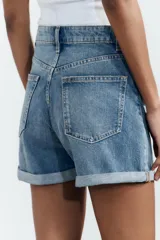 Bermuda de jean celeste, corte mom fit, tiro alto, con cinco bolsillos y ruedo doblado.