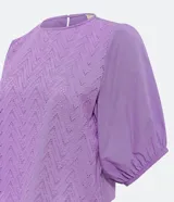Blusa de laise color lila con mangas cortas abullonadas, cuello redondo y textura cutout.