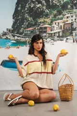 Remera de tejido calado color crudo con rayas horizontales rojas y terminaciones marrones, con cierre frontal y logo bordado.