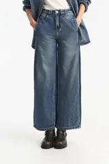 Jean de mezclilla azul de tiro medio, corte ancho y pierna recta, con efecto desgastado en el frente.