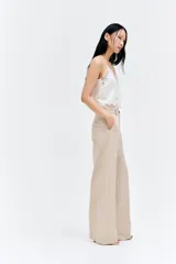 Pantalón de corte holgado color beige, confeccionado en mezcla de lino. Modelo de tiro alto con cierre y botón, bolsillos al bies, bolsillos insertados atrás y piernas amplias.